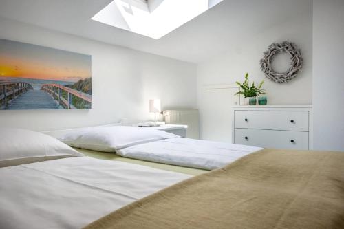 AlbertsdorfKnusthof - Wohnung 1的一间白色卧室,配有两张床和墙上的绘画