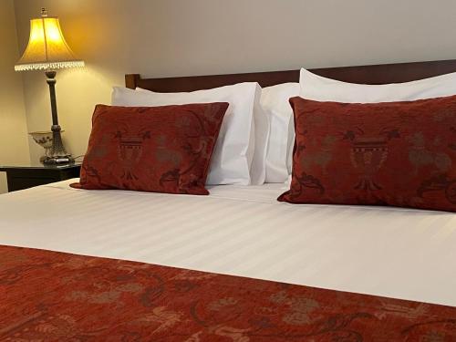 卢拉Burradoo Studio的一张带白色床单和红色枕头的床