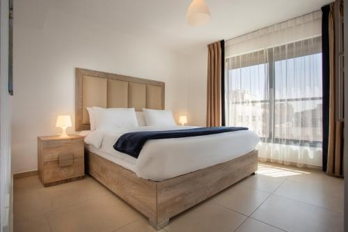 安曼Triple A Hotel Suites的一间卧室设有一张大床和一个大窗户