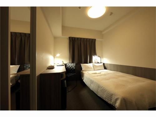 仙台Sendai Business Hotel Ekimae的配有一张床和一张书桌的酒店客房