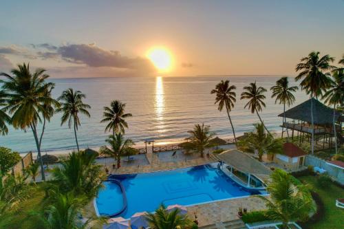 乌罗阿Sunny Palms Beach Bungalows的享有带游泳池和海洋的度假村的空中景致