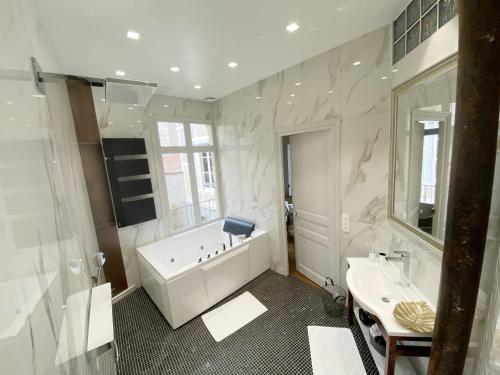 兰斯Le Clovis Suites Spa Sauna的白色的浴室设有浴缸和水槽。