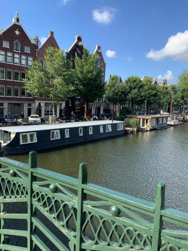 阿姆斯特丹Boat no Breakfast的蓝色的船停靠在河上,河上建有建筑物