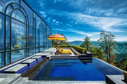 西姆拉Wildflower Hall, An Oberoi Resort, Shimla的一座带游泳池和遮阳伞的房子