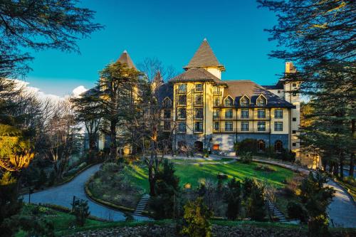 西姆拉Wildflower Hall, An Oberoi Resort, Shimla的前面有大院子的大房子