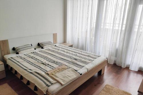 德布勒森Pláza Apartman - city center, free parking, free wifi的卧室配有一张带白色窗帘的大床