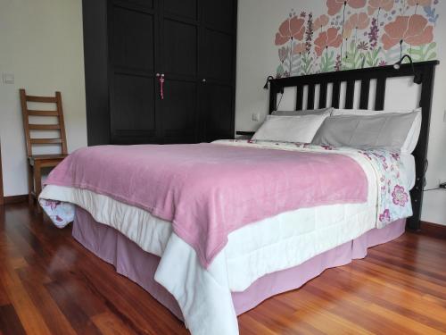 波特斯APARTAMENTO VALMAYOR的一间卧室配有一张大床,配有粉色和白色的床罩