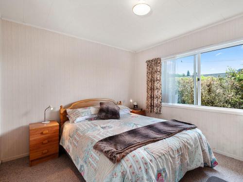 陶波Central Riverside Retreat - Taupo Holiday Home的一间卧室设有一张床和一个大窗户