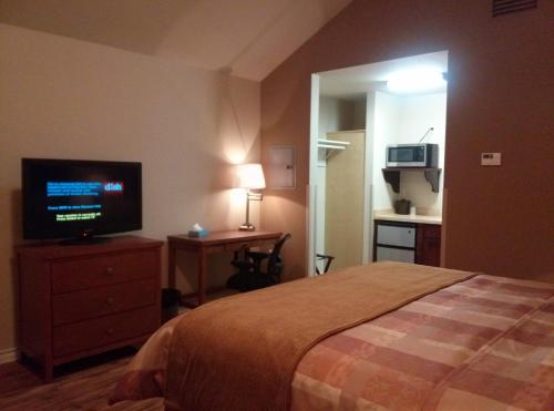 KenedyFieldHouse Inn & Conference Center的一间卧室配有一张床和一台平面电视