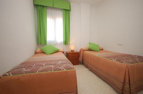桑卢卡尔-德巴拉梅达Holi-Rent Albatros的一间卧室设有两张床,窗户设有绿色窗帘