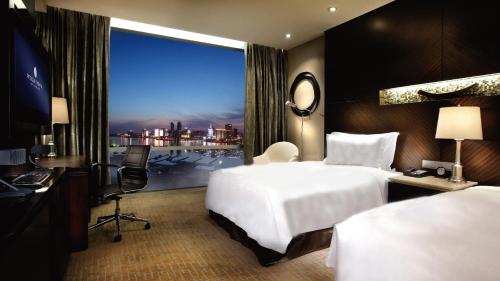青岛青岛海尔洲际酒店（奥林匹克帆船中心内）的酒店客房设有一张白色大床和一个窗户。