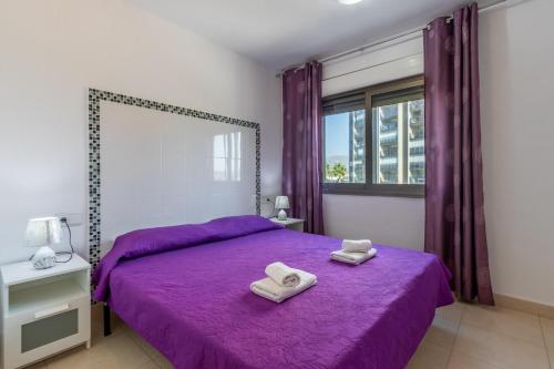 卡尔佩Bahia del Sol的一间卧室配有一张紫色床和两条毛巾