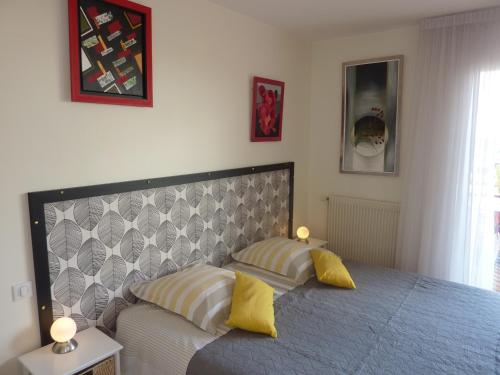 CébazatLes Terrasses de Bellemoure Cébazat的一间卧室配有一张带两个黄色枕头的床