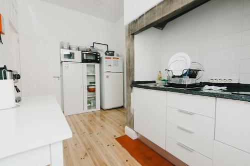 丰沙尔Jaca Hostel Funchal的铺有木地板的厨房配有白色家电