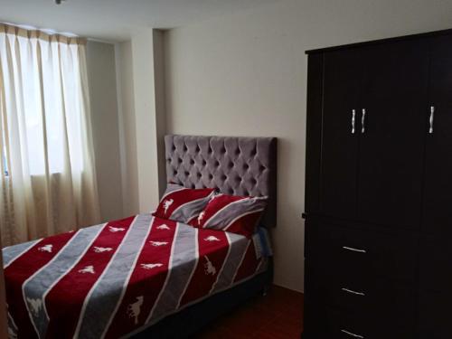 利马201 Departamento exclusivo en Chorrillos的一间卧室配有一张带红色和灰色毯子的床