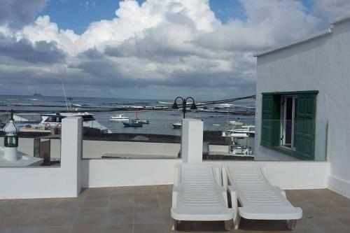 奥尔索拉Apartamentos Los Vientos (Apto 8)的阳台配有白色椅子,享有水景。