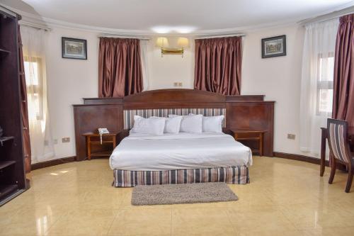 阿克拉Sonia Hotel的一间卧室配有一张大床和木制床头板