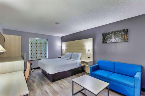 萨凡纳Days Inn by Wyndham Savannah Gateway I-95的酒店客房,配有床和蓝色的沙发