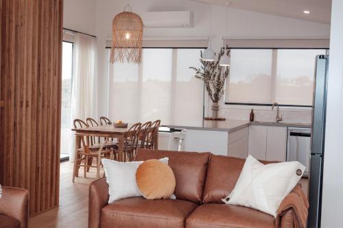 坎贝尔港Ocean Oasis Port Campbell的一间带棕色沙发的客厅和一间厨房