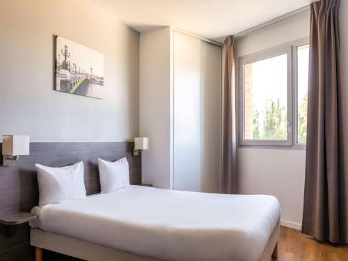马恩河畔诺让马恩河畔诺让阿德吉奥阿克瑟斯公寓式酒店的一间卧室设有一张大床和一个窗户。