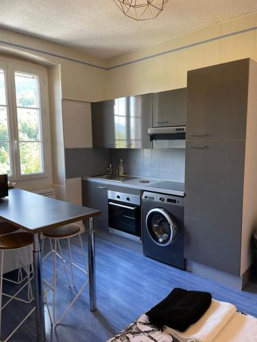 艾格布莱特勒拉克Beau séjour的厨房配有桌子、洗衣机和烘干机