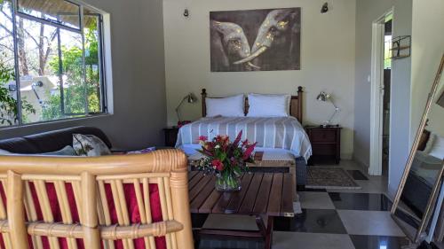 卡萨内Sunbirds Cottage的一间卧室配有一张床和一张鲜花桌子