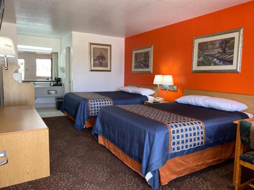 布里奇波特GreyStone Inn的橙色墙壁的酒店客房内的两张床