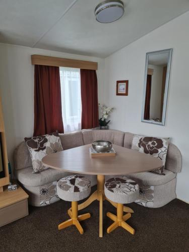 康福斯Carmels Caravan Borwick Lakes的客厅配有桌子和沙发