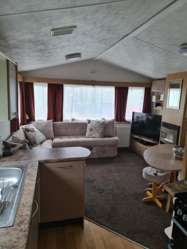 康福斯Carmels Caravan Borwick Lakes的厨房以及带沙发的起居室。