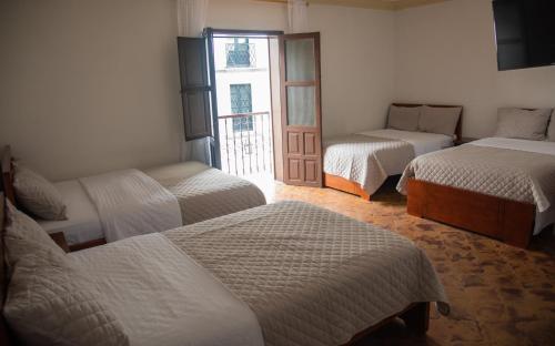 波帕扬Hotel Lili - Popayán的带三张床的客房和一扇窗户的门