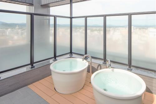 旭川HOTEL AMANEK Asahikawa的一间带浴缸的浴室,位于带窗户的客房内
