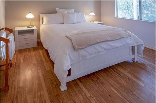 Harewood阿比韦尔农场度假屋的卧室铺有木地板,配有一张白色的床。