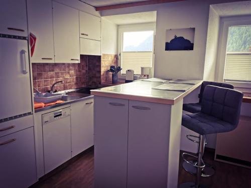 萨姆瑙恩Haus Crestas的厨房配有白色橱柜、水槽和椅子