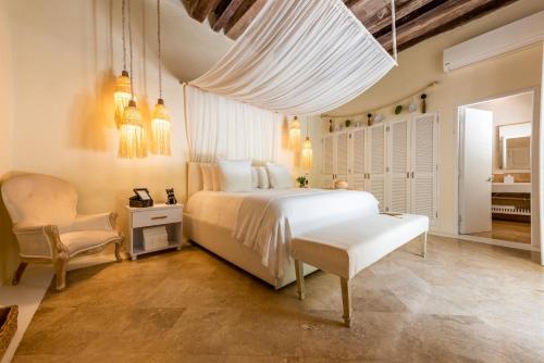 卡塔赫纳Casa Diluca Cartagena Hotel Boutique的卧室配有白色的床和椅子