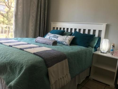 比勒陀利亚Smart Studio with Netflix and no load shedding的一间卧室配有一张带蓝色枕头的床和一扇窗户。