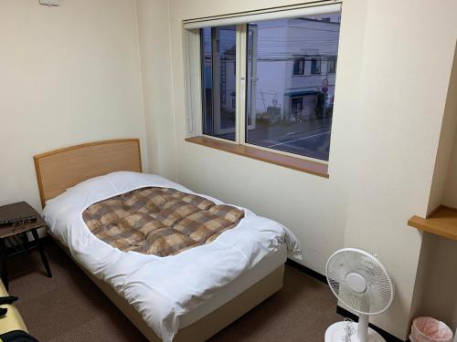 稚内山一日式旅馆的一间卧室设有一张床和一个窗口