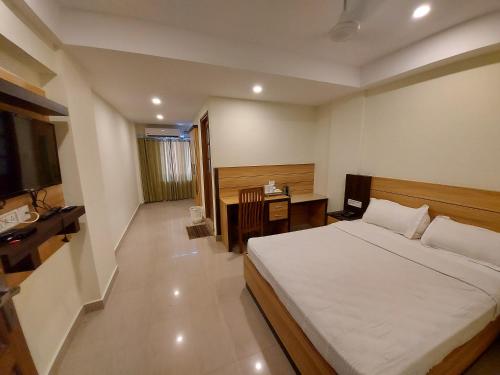 古鲁瓦尤尔Hotel Sree Gokulam Apartments的一间卧室配有一张床和一张书桌