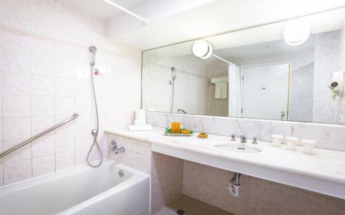 塔穆宁Pacific Islands Club Guam的一间带水槽、浴缸和镜子的浴室