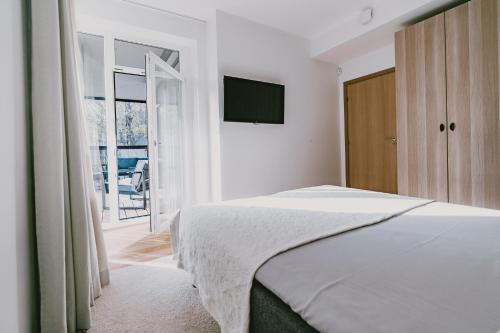 塔尔图ÖÖ Street Premium Apartment with Terrace的一间白色卧室,配有床和电视