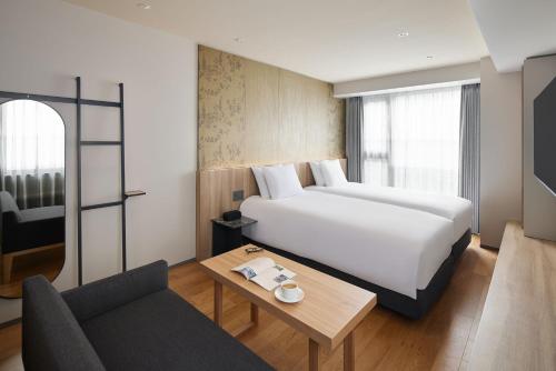 京都Oakwood Hotel Oike Kyoto的酒店客房配有床、桌子和沙发。