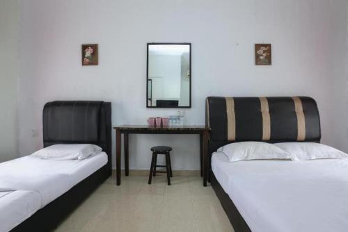 哥打巴鲁Cerana Villa Eco Resort的配有一张桌子和镜子的客房内的两张床