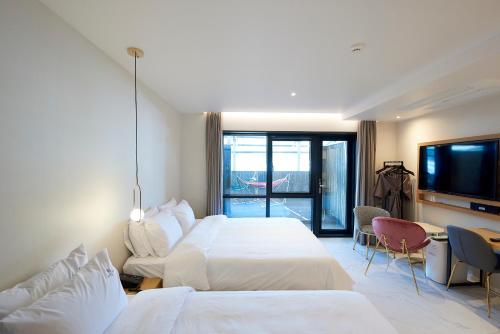 釜山BONATHREE HOTEL的酒店客房设有两张床和一台平面电视。