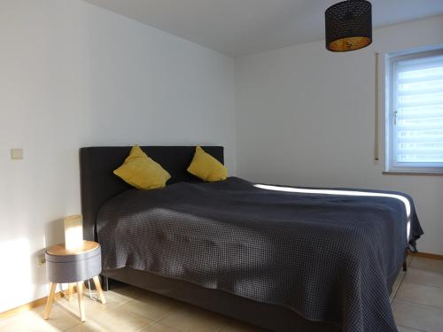 GaukönigshofenExclusive cozy apartment in the heart of Franconia的一间卧室配有黑色床和黄色枕头