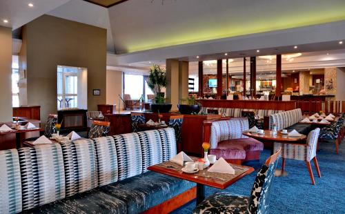 布隆方丹City Lodge Hotel Bloemfontein的一间带桌椅的餐厅和一间酒吧