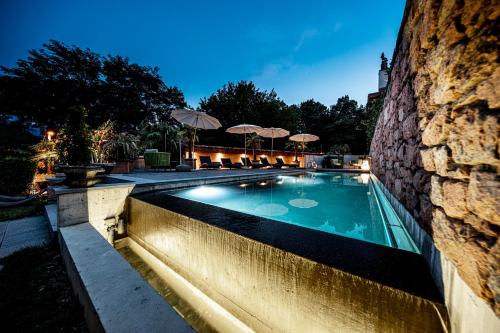 卡罗纳Swiss Historic & Garten Hotel Villa Carona的一座游泳池,旁边是一座建筑,设有石墙