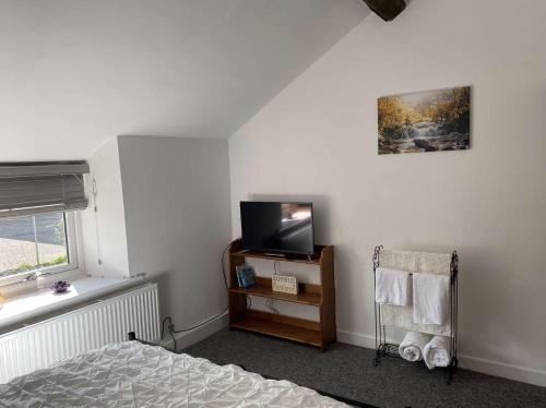 里辛Rhos cottage Ruthin的卧室配有一张床,墙上配有电视。