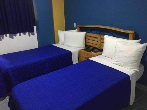 加拉加斯Hotel Renovación的两张位于酒店客房的床,拥有蓝色的墙壁