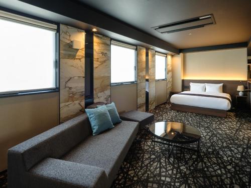 滨松Hotel Act Garden HAMAMATSU的酒店客房设有一张沙发和一张床