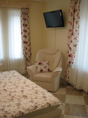 布达佩斯Aranyosház-Vendégház的卧室配有椅子和墙上的电视