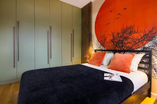 科沙林W&K Apartments - Balance Suite的卧室配有一张床铺,墙上挂有橙色画
